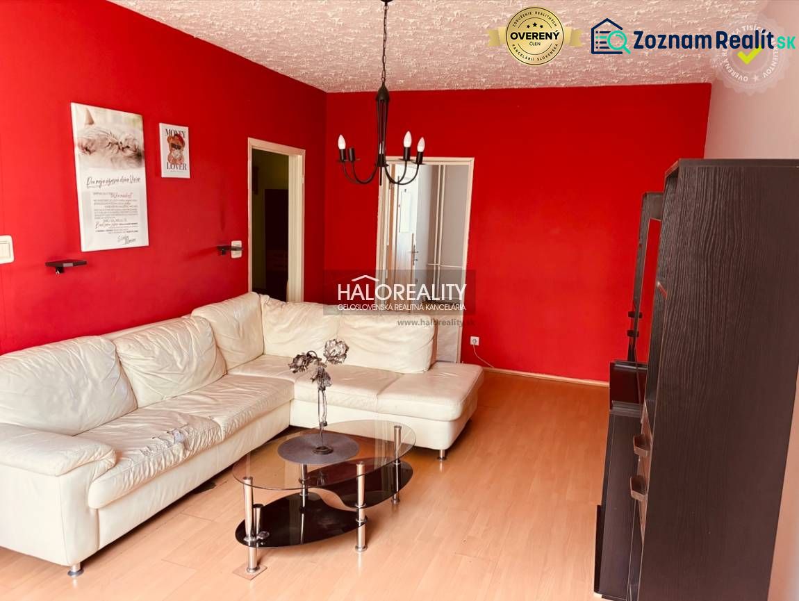 Living room in a 3-room apartment with a white couch, red walls, and a glass table.