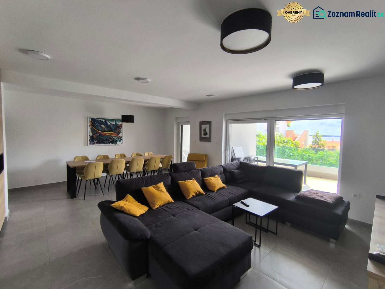 Living room in a 4-room apartment with a large sofa, dining table, and a view of the terrace.
