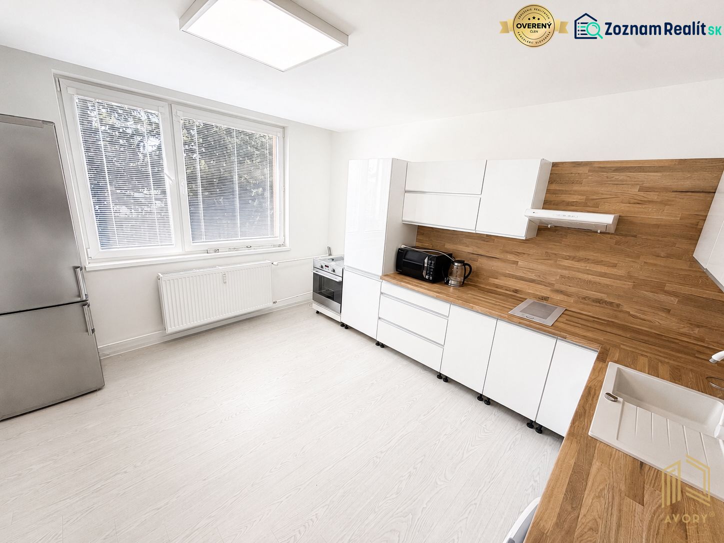A kitchen in a studio apartment with white cabinets and wood-patterned flooring.