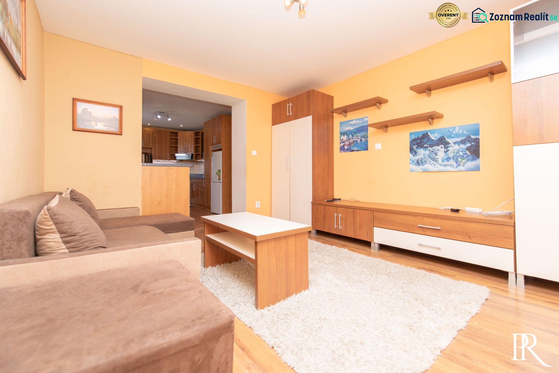 Living room in a two-room apartment with a sofa, furniture, and a view into the kitchen.