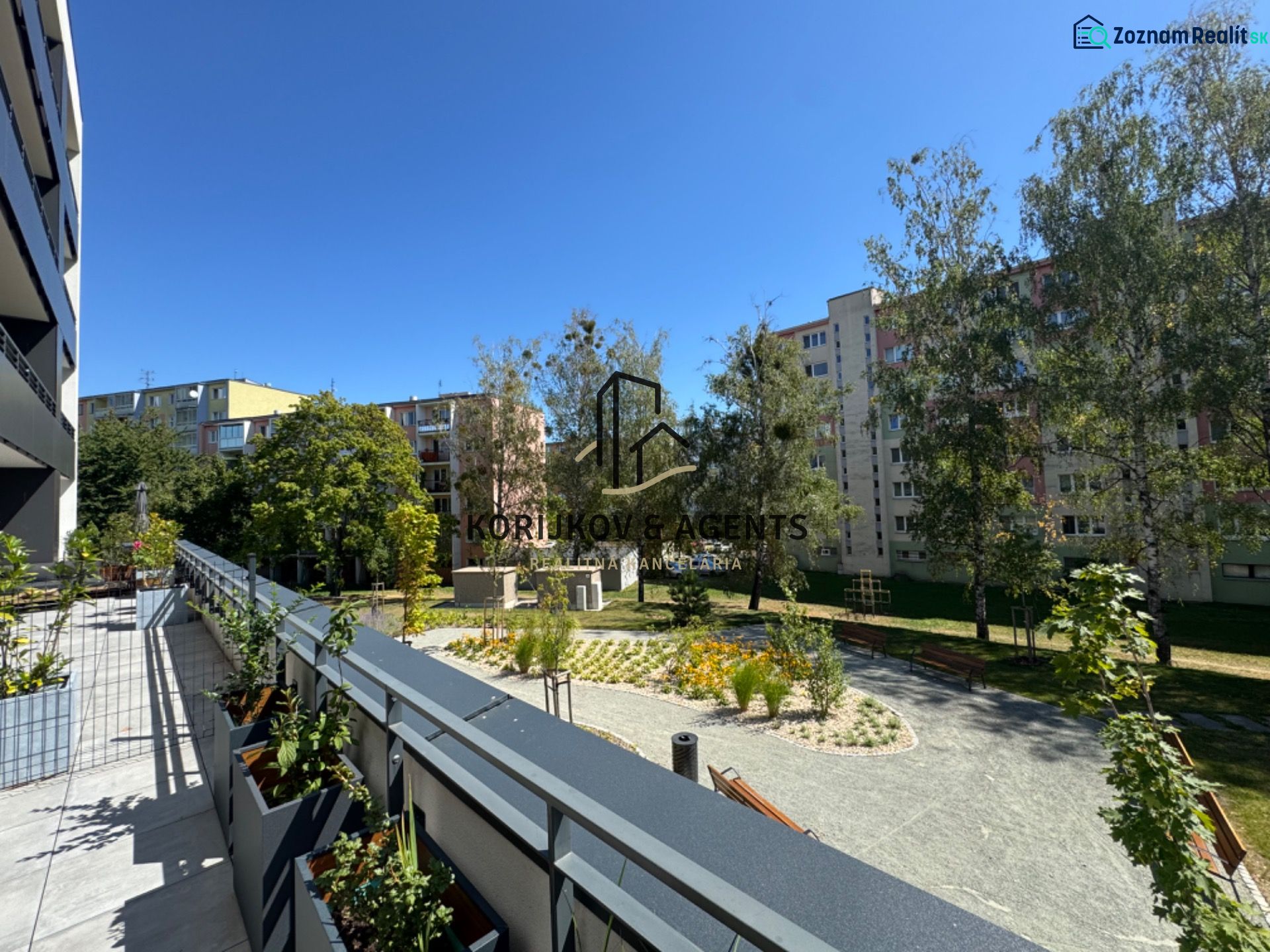 View of greenery and apartment buildings from the balcony on Popradská Street in Košice.