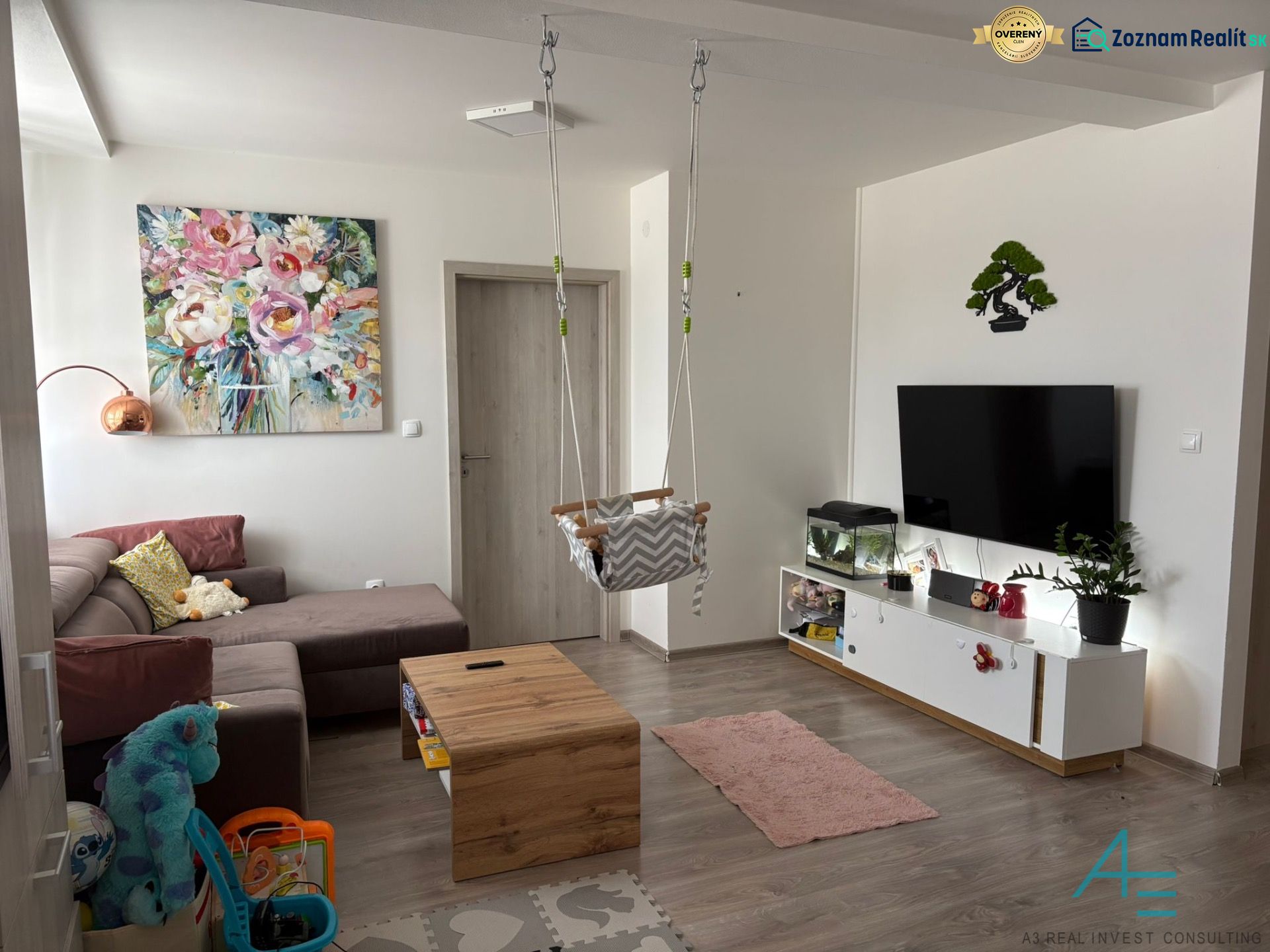 Living room in a two-room apartment with a play corner and a floor with a wooden decor.