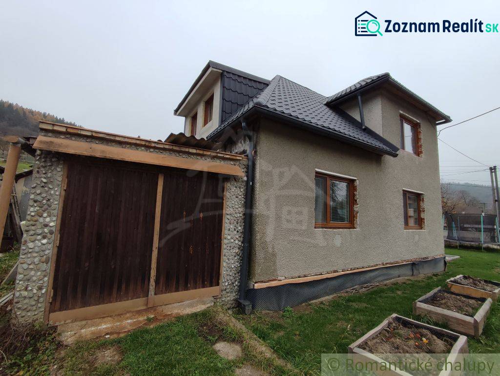 A family house in Jasenica with a wooden garage and garden planters on the lawn.