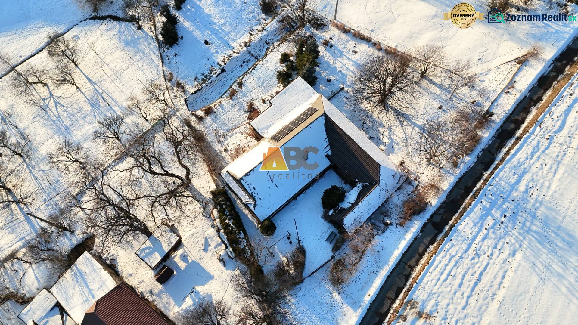 A snow-covered cottage on Zánemecká Street in Hriňová surrounded by trees and nature.