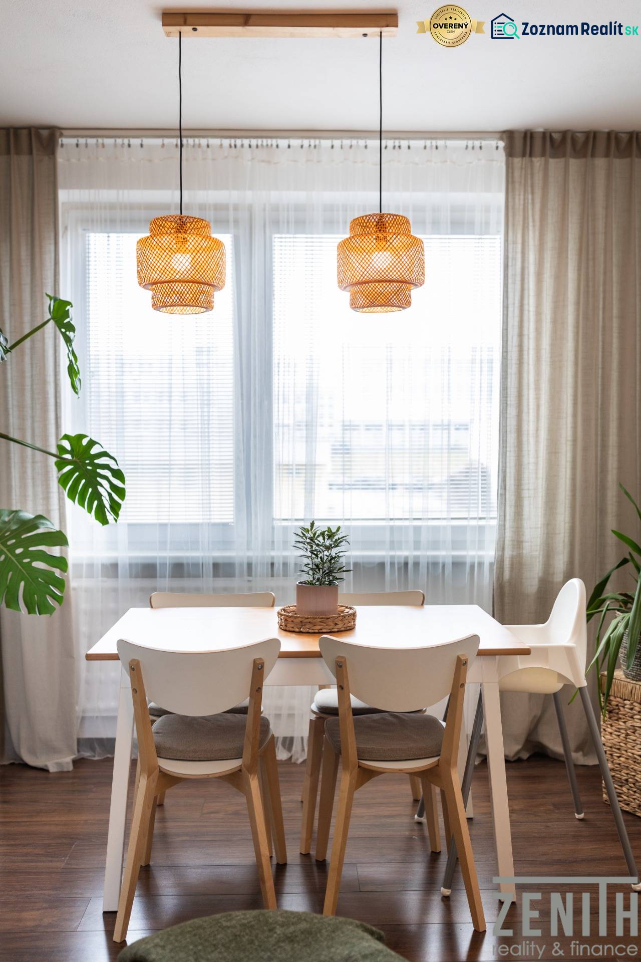 Dining area with a table, chairs, and a plant in a 3-room apartment with wooden decor flooring.
