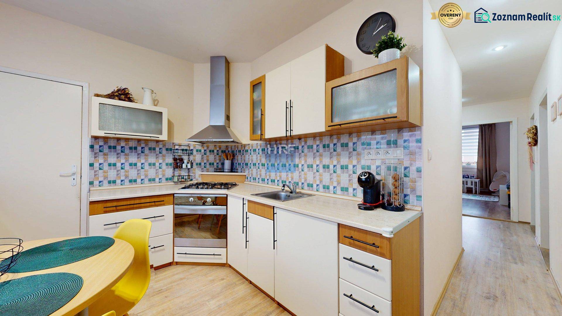 A kitchen in a 3-room apartment with colorful tiles and a wooden decor floor.