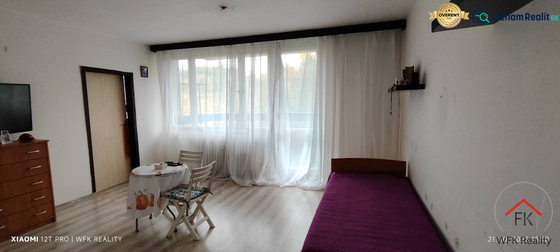 A room in a three-room apartment with a bed, table, chairs, and a floor with a wooden decor.