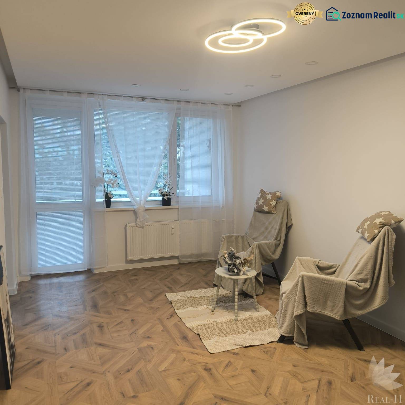 Living room in a 4-room apartment with a wooden decor floor, armchairs, and decorations.