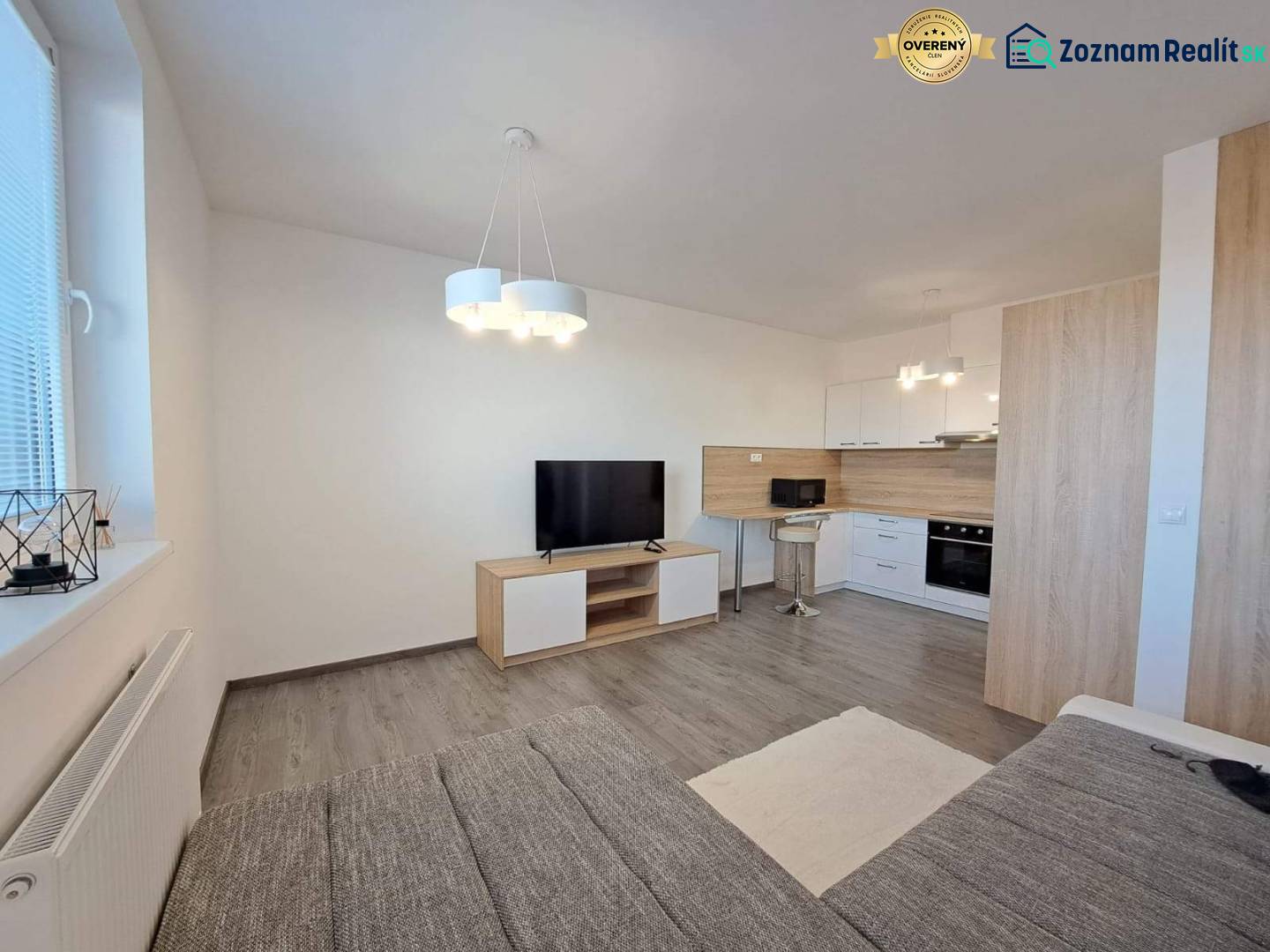 Living room in a 2-room apartment. Modern kitchen, TV, wooden decor flooring.