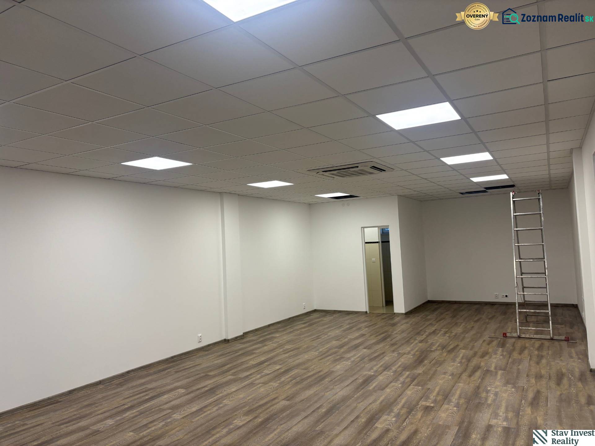 Commercial premises with wood-patterned flooring, ceiling lighting, ladder.