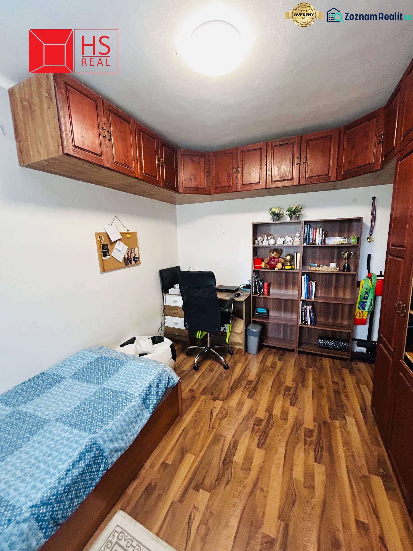 A room in a 3-room apartment contains a bed, a shelf, a desk, and a floor with a wooden decor.