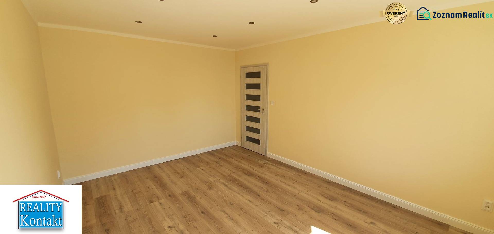 A bright room with a wooden decor floor and a door in a two-room apartment.