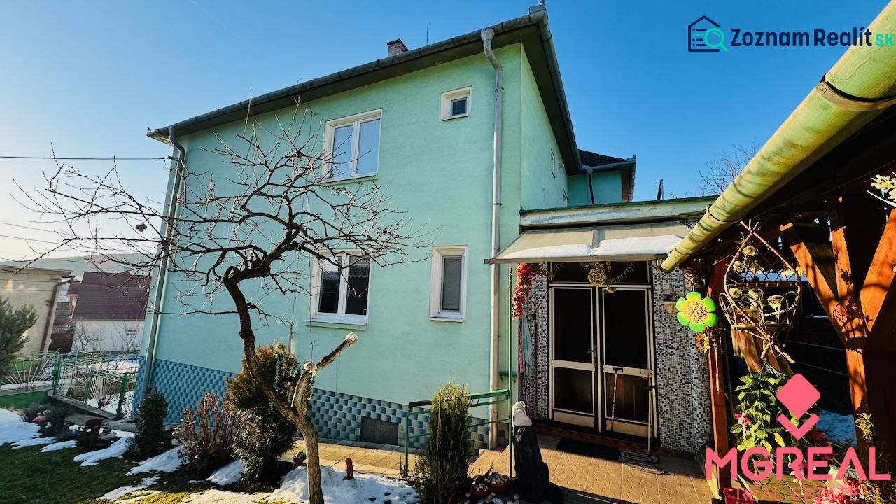 A family house in Horná Ves with a green facade, a garden with remnants of snow.
