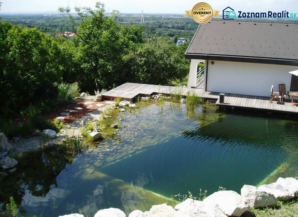A family house in Hainburg an der Donau with a natural pool by the terrace surrounded by greenery.
