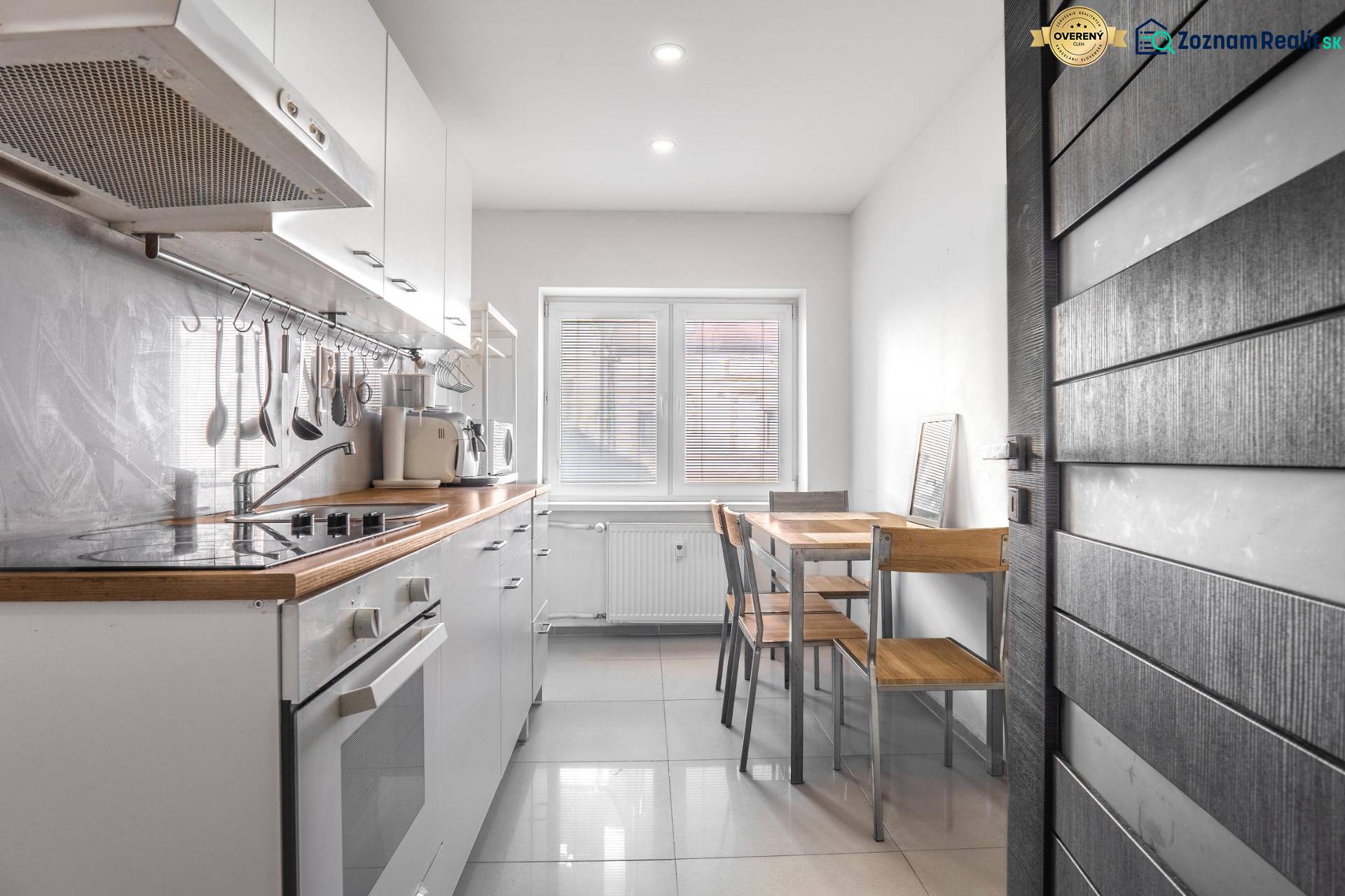 A kitchen in a 3-room apartment with white cabinets and a dining table by the window.