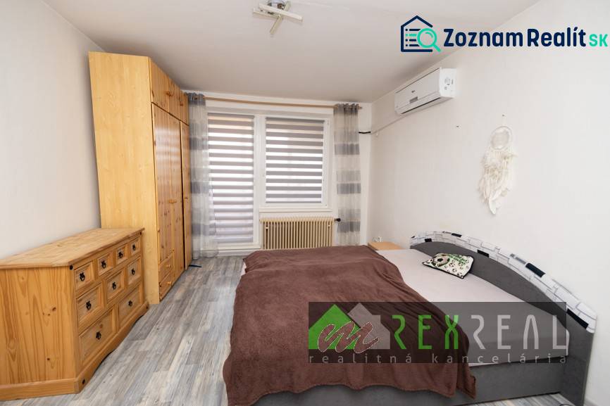 Bedroom in a 3-room apartment with wood-patterned flooring, a wardrobe, and a bed.