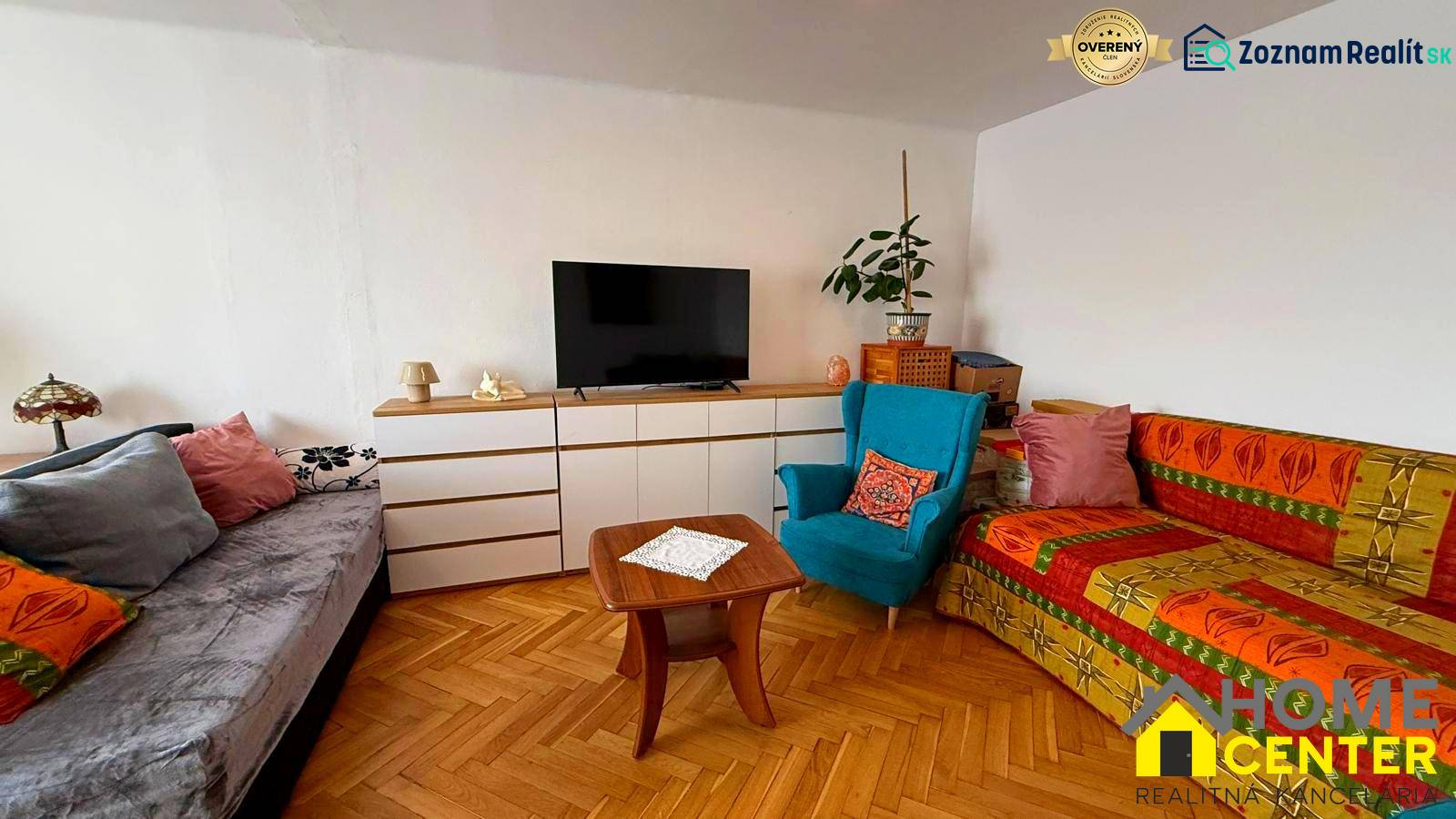 Living room in a three-room apartment with a wooden decor floor, sofas, and a television.