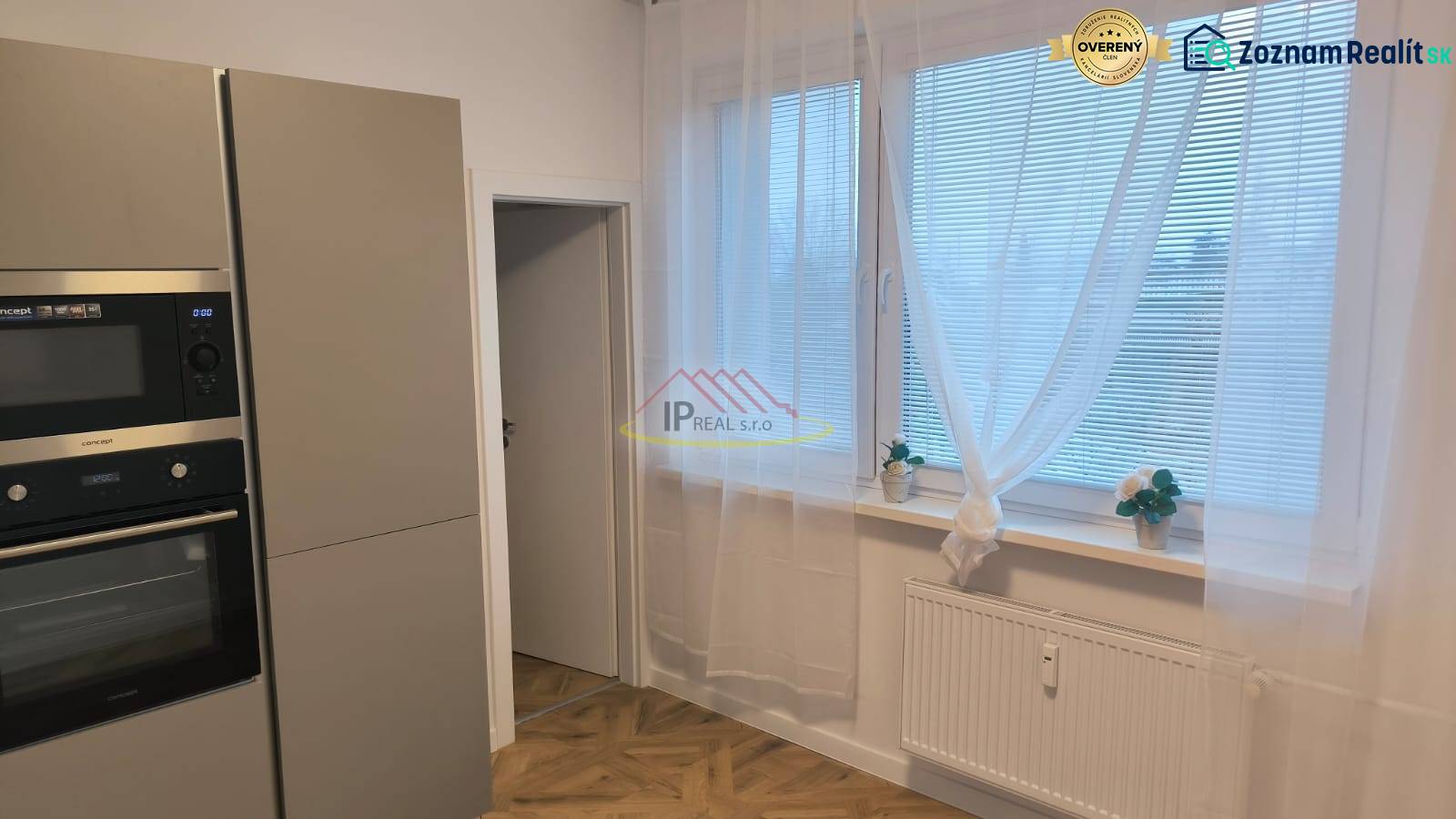 Kitchen in a 4-room apartment with a microwave, large windows, and a wooden decor floor.