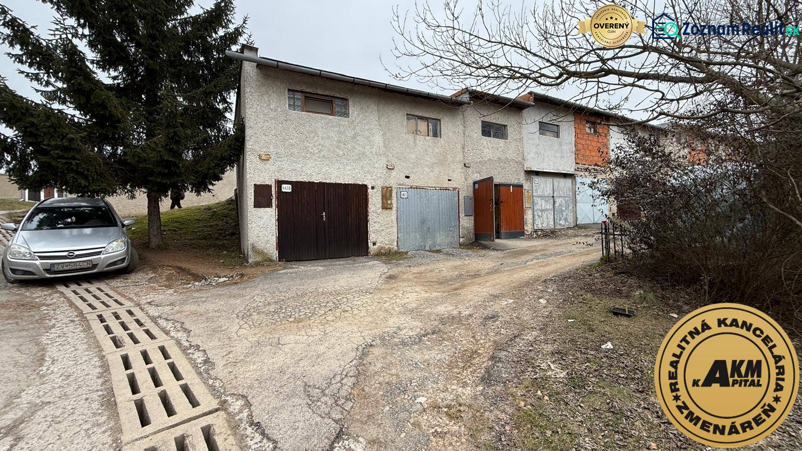 Garages on Prachatická Street in Zvolen with the real estate agency's sign.