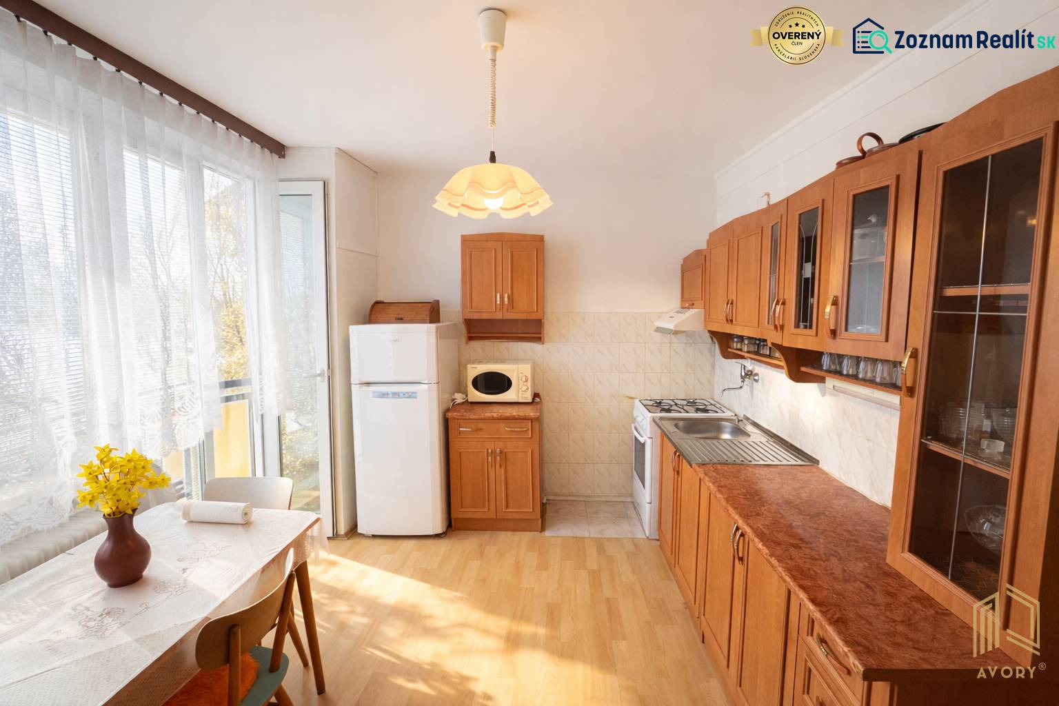 A kitchen in a three-room apartment with a wooden decor floor and a kitchen unit.