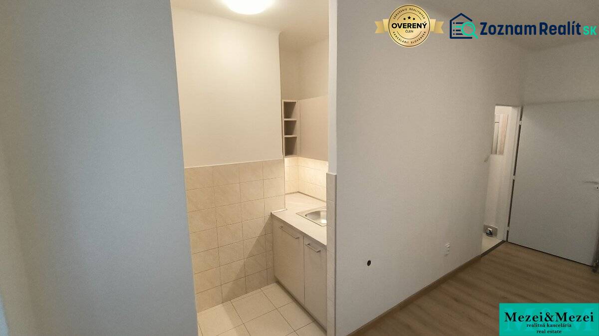 Kitchen corner in a studio apartment with a wooden decor floor and light tiles.