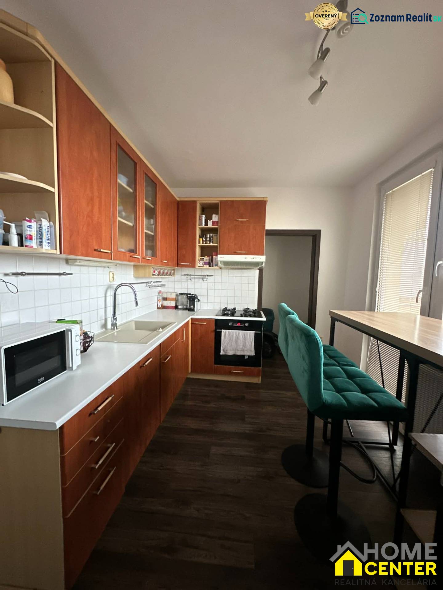 Kitchen in a 4-room apartment with wood-patterned flooring, green chairs, built-in cabinets.