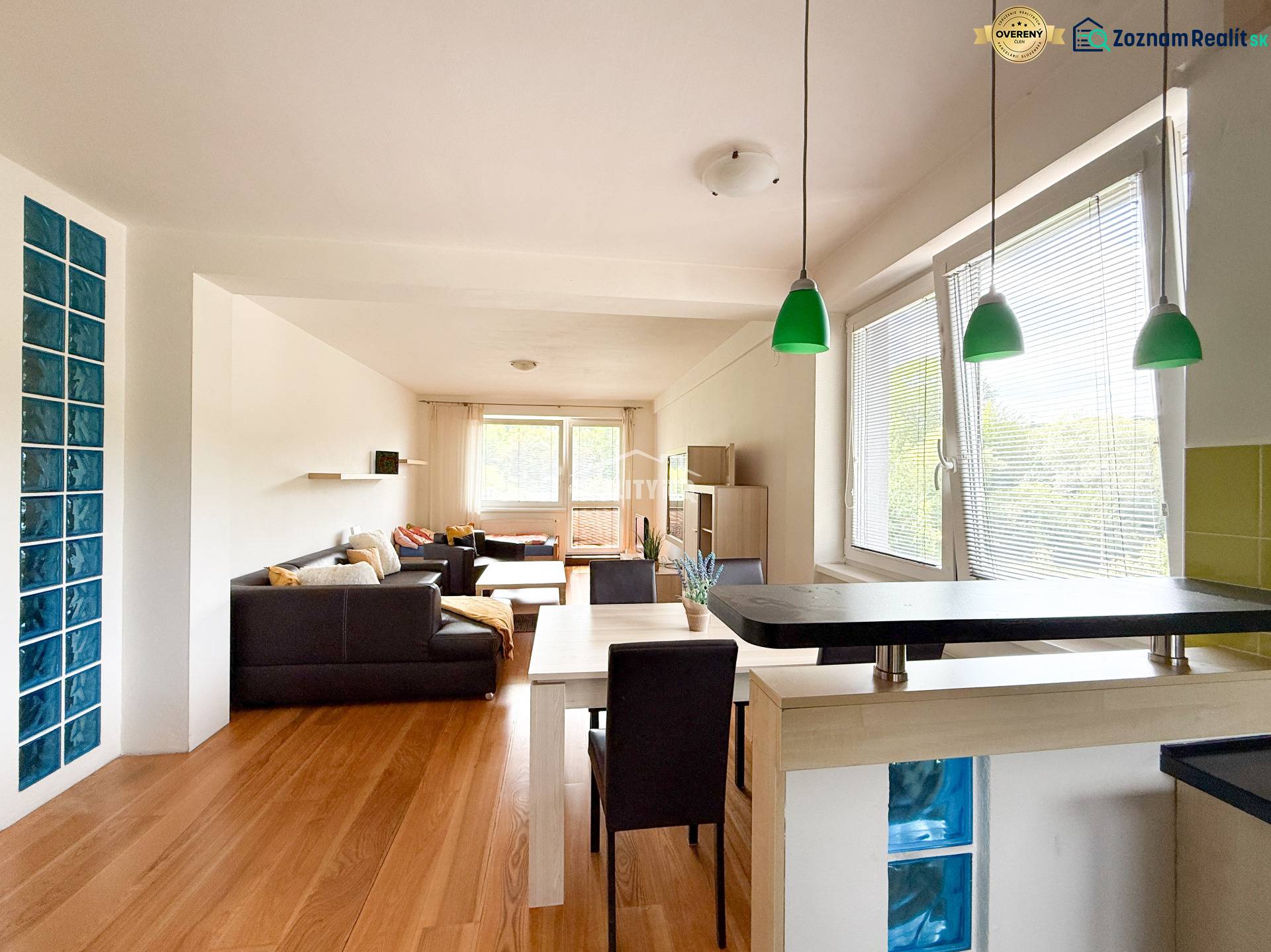 Living area of a 2-room apartment with a wooden decor floor and green lighting fixtures.