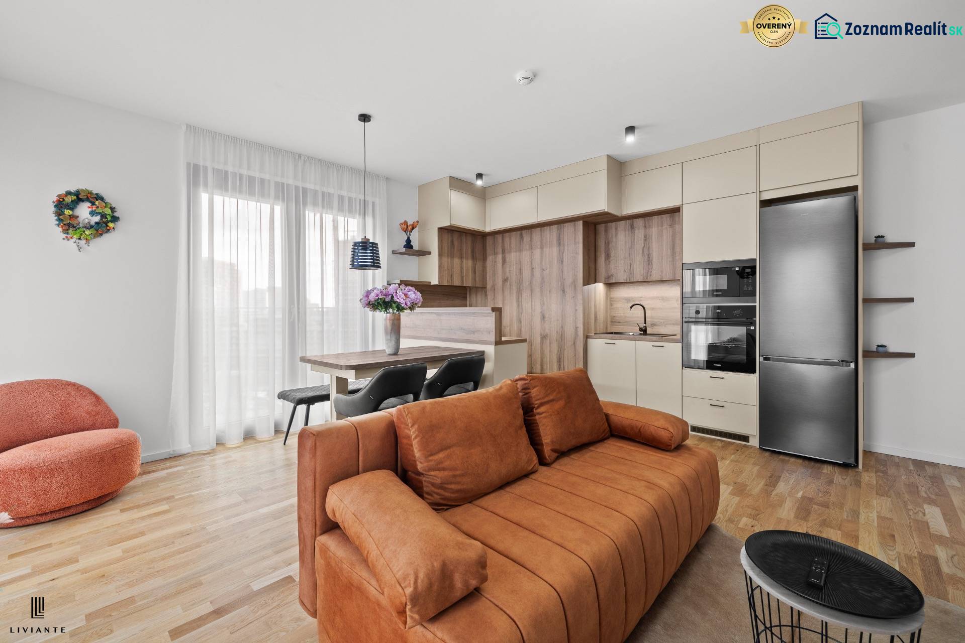 A kitchen in a 3-room apartment with a wooden decor floor and a comfortable orange sofa.