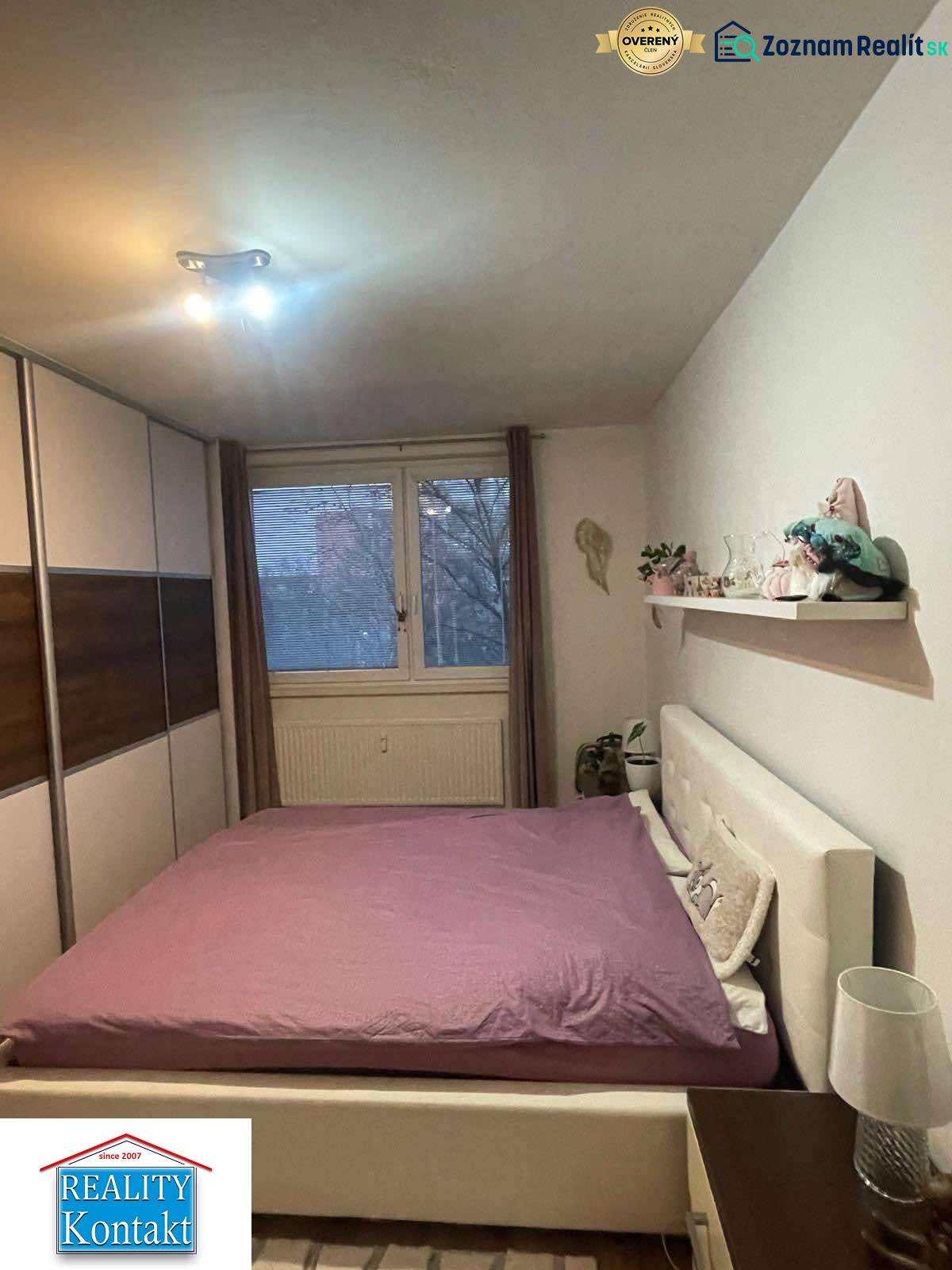 Bedroom in a two-room apartment with a double bed and a built-in wardrobe, floor with wood decor.