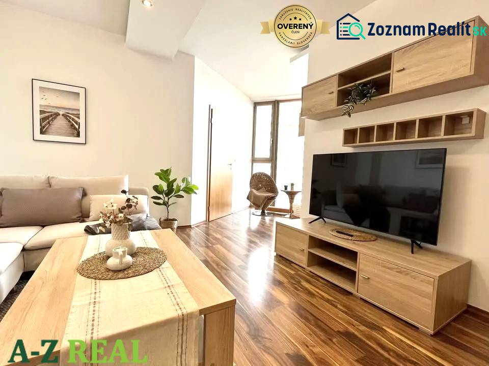 Living room in a three-room apartment with a wooden decor floor and simple furnishings.