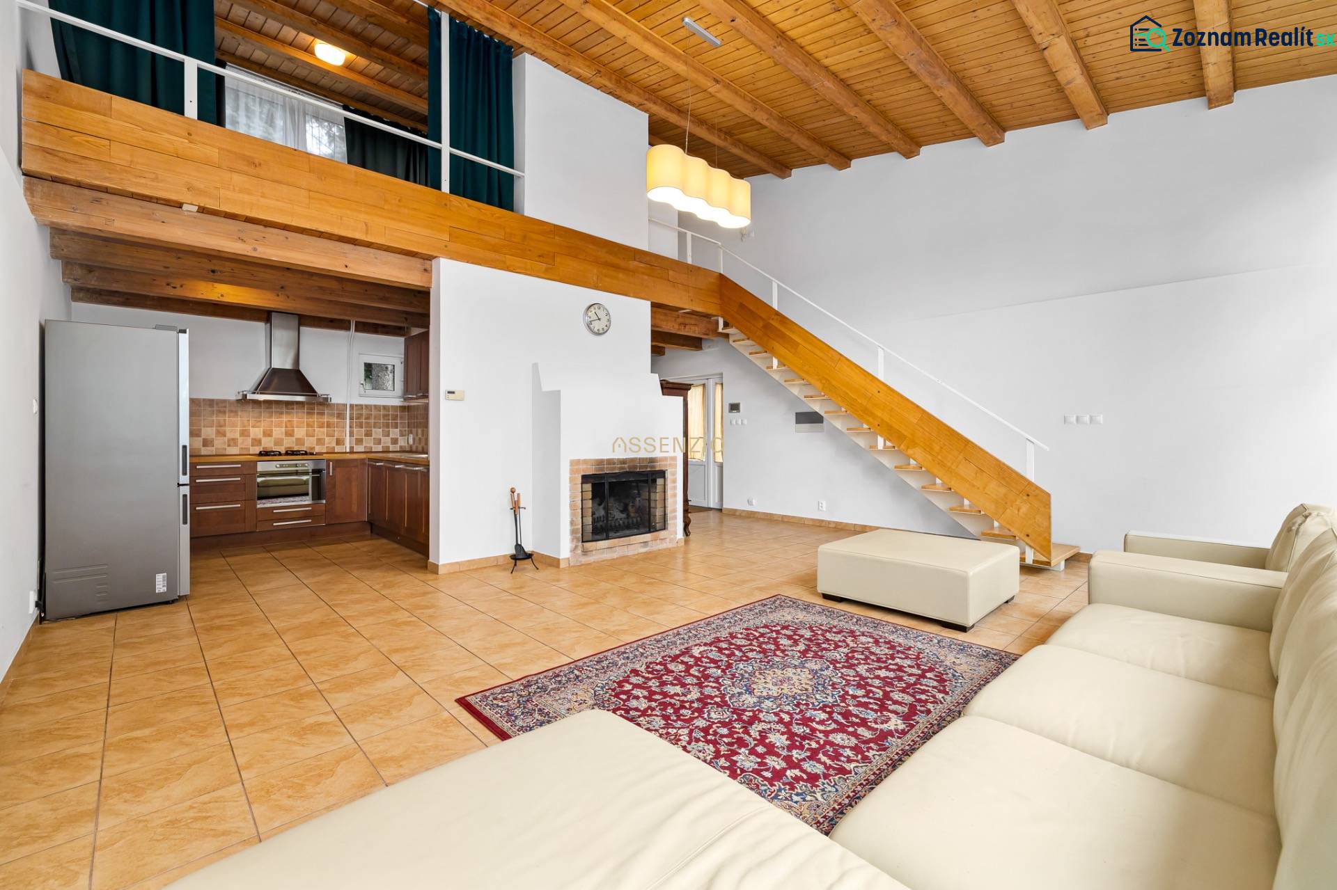 Living room with a fireplace and kitchen, wooden decor flooring, stairs to the attic.