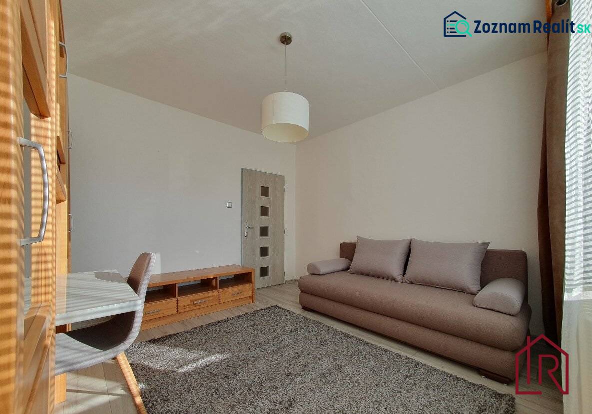 Living room in a three-room apartment with a sofa, carpet, and floor with a wooden decor.