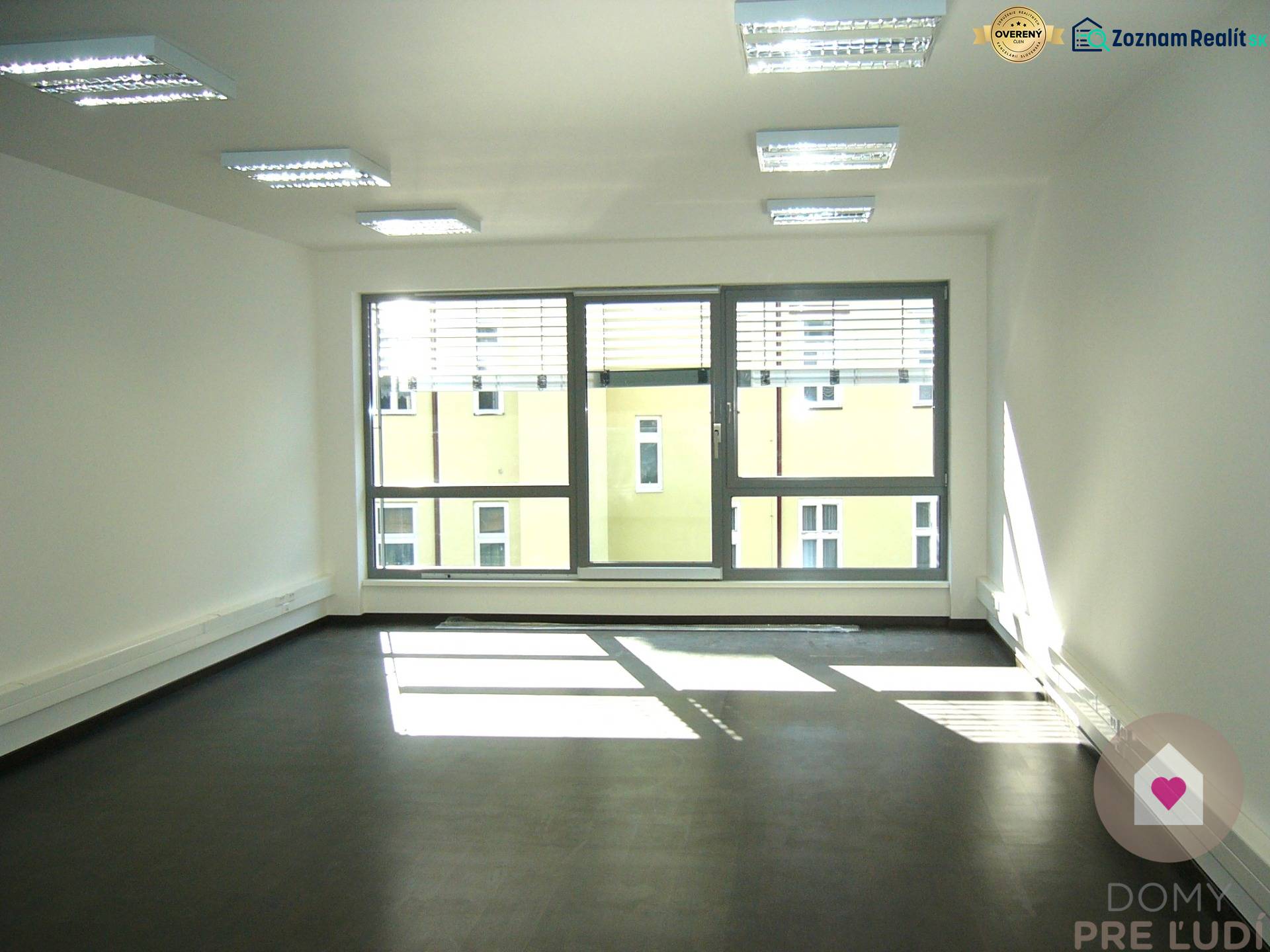 A bright office with a large window and a wooden decor floor.