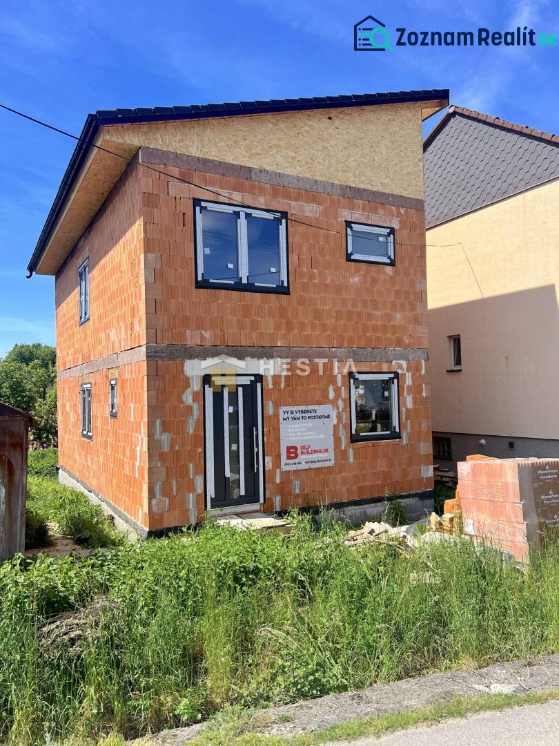 Unfinished family house in Cerová with unplastered brick walls and black window frames.
