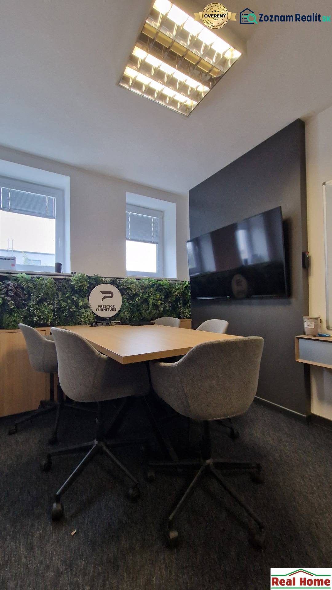 Office seating with a conference table, gray chairs, and green wall decoration.