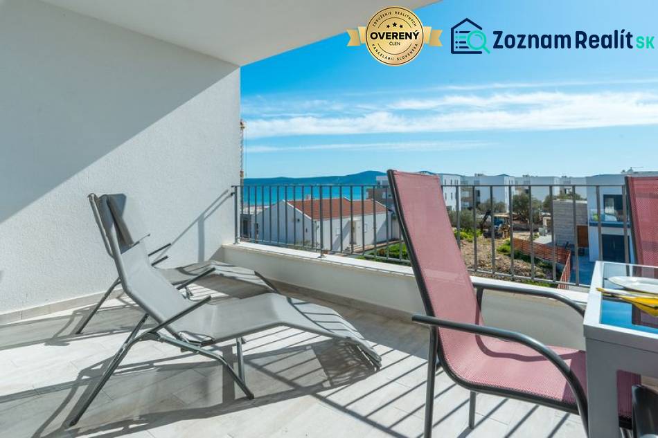 Terrace of a 3-room apartment in Sukošan with a sea view, folding chairs, clear sky.