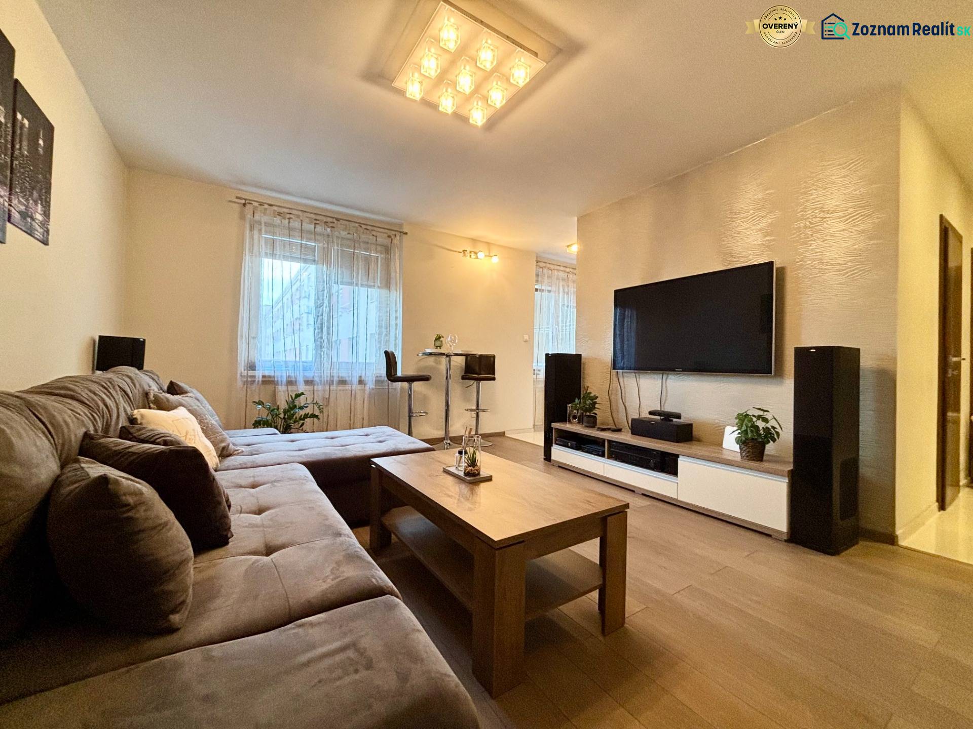 Living room in a two-room apartment with a sofa and a television, floor with wood decor.