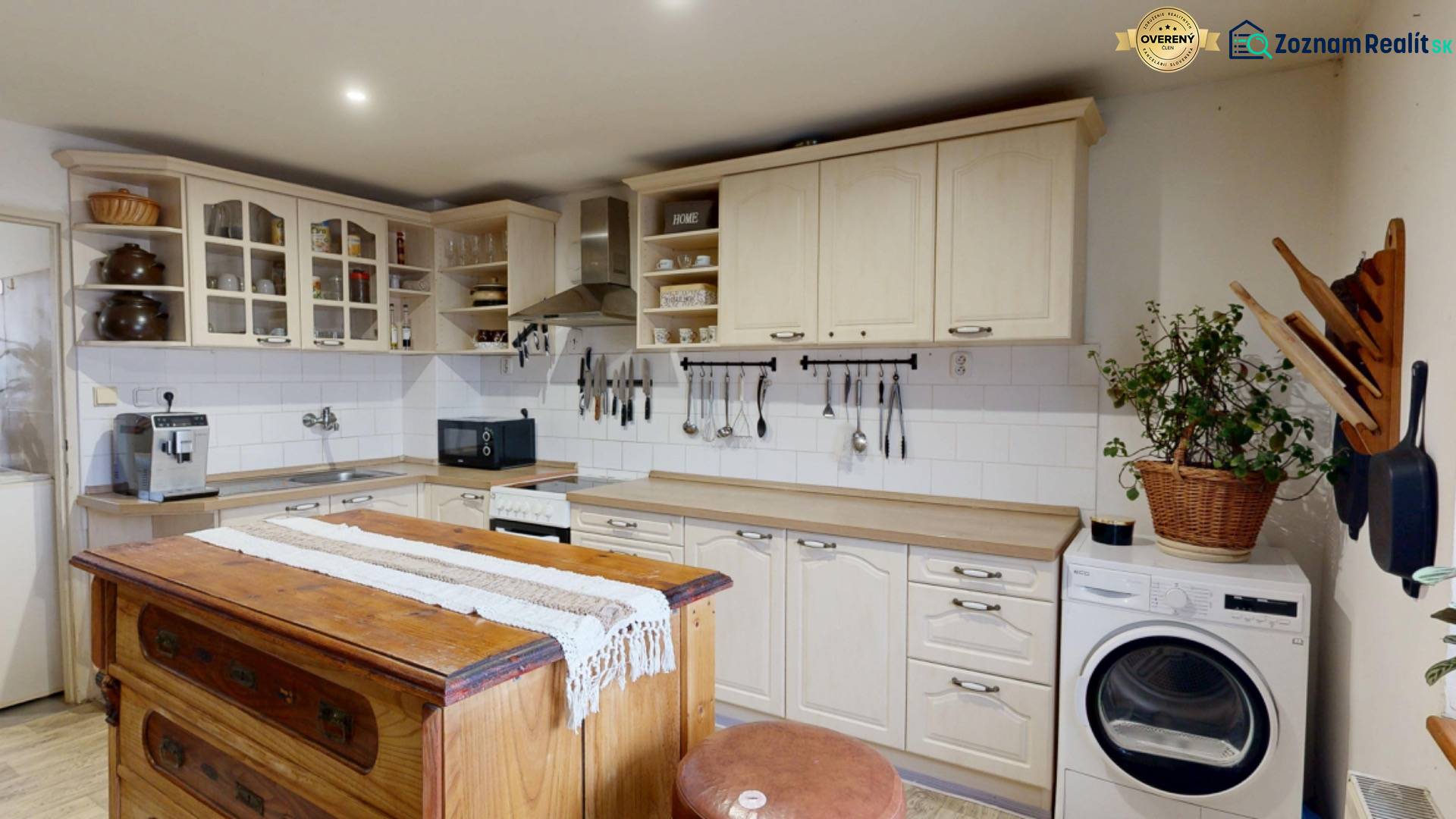 A kitchen with a vintage island, kitchen cabinets, a sink, and a washing machine in a family house.