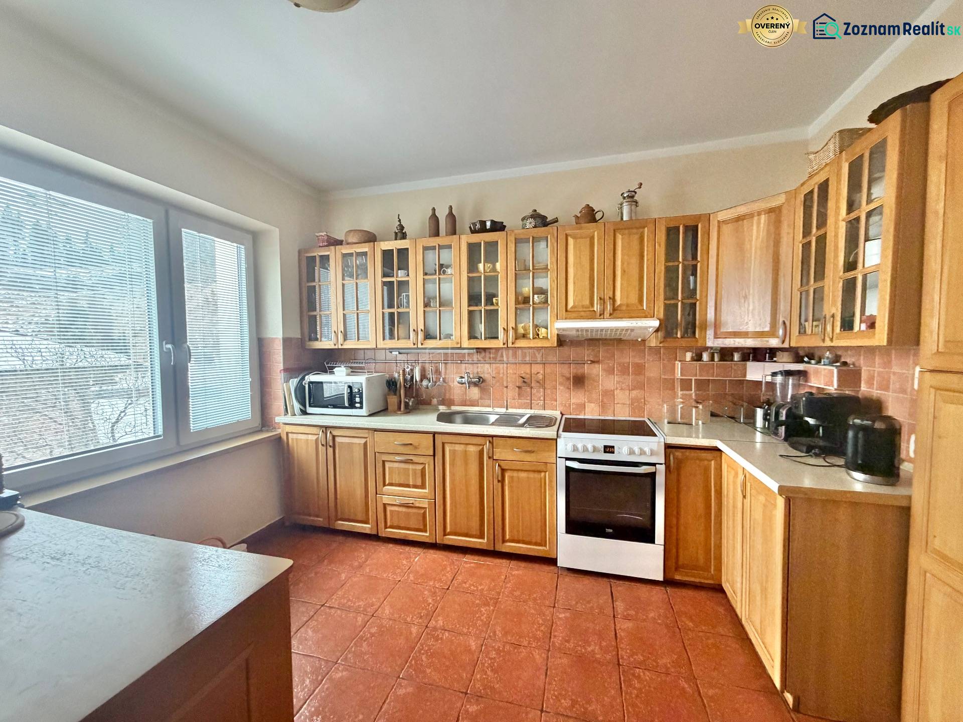 A kitchen with a corner wooden unit and appliances in a family house.