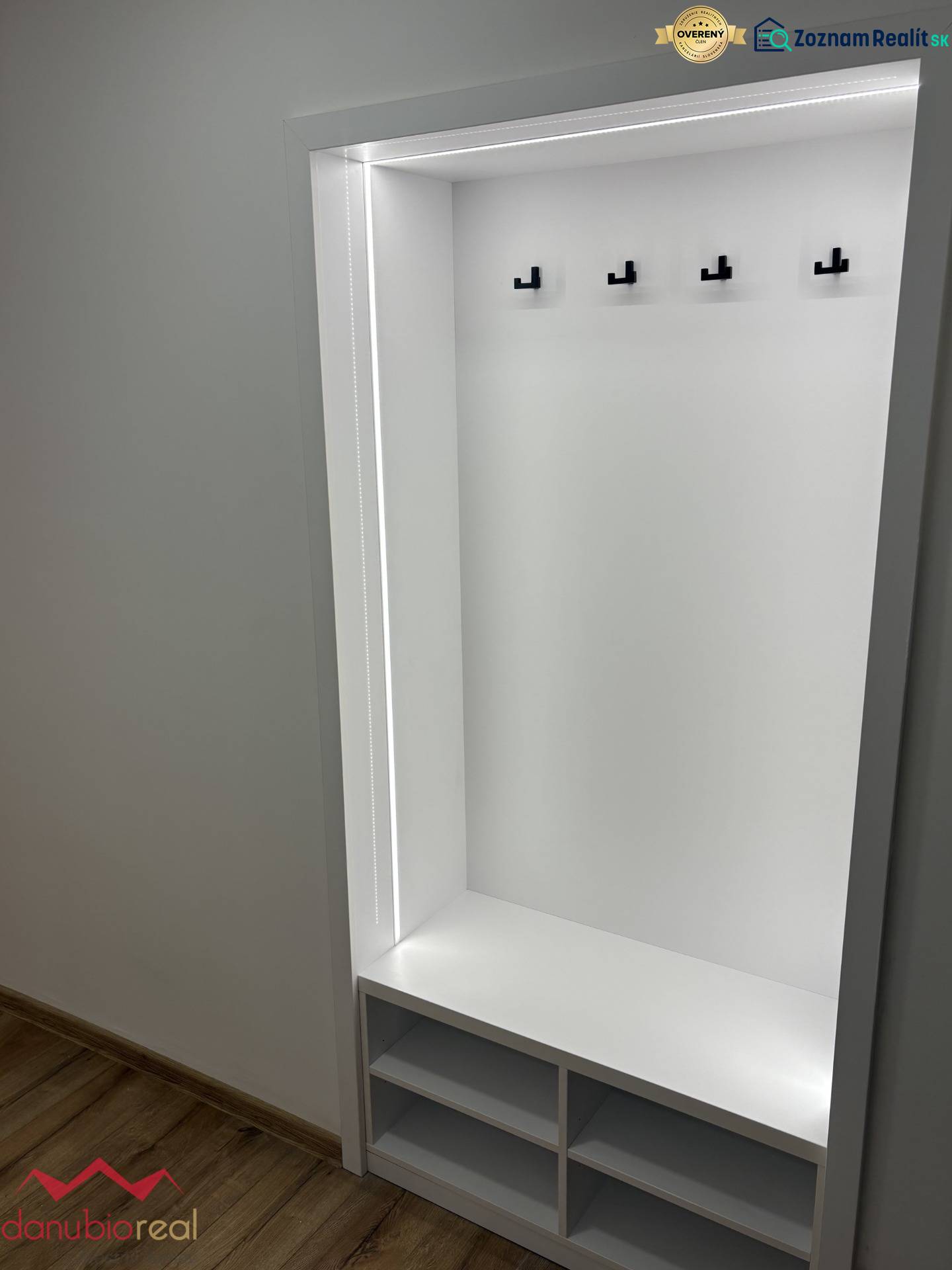 Built-in hallway wardrobe in a 3-room apartment with hooks and a floor with a wood decor.
