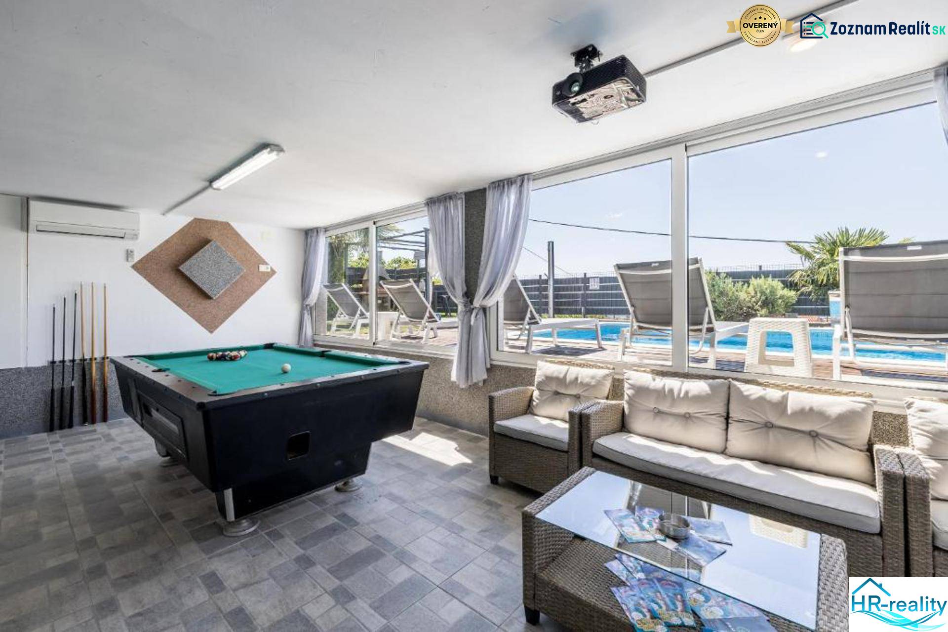 Interior of a villa with a billiard table and a view of the pool.