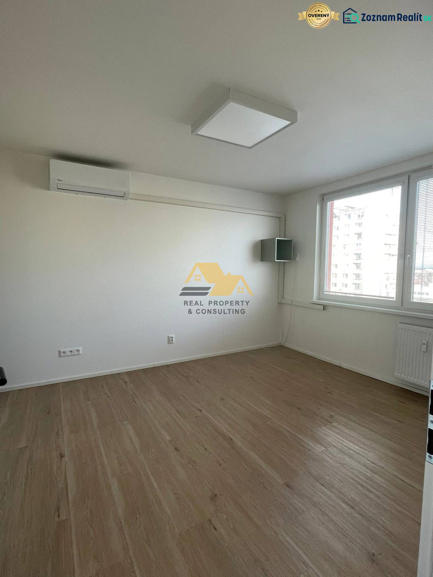 A room with white walls and a wooden decor floor in a studio apartment.