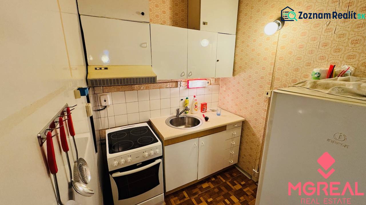 Kitchen in a 2-room apartment, white cabinets, stove, sink, floor with wood decor.