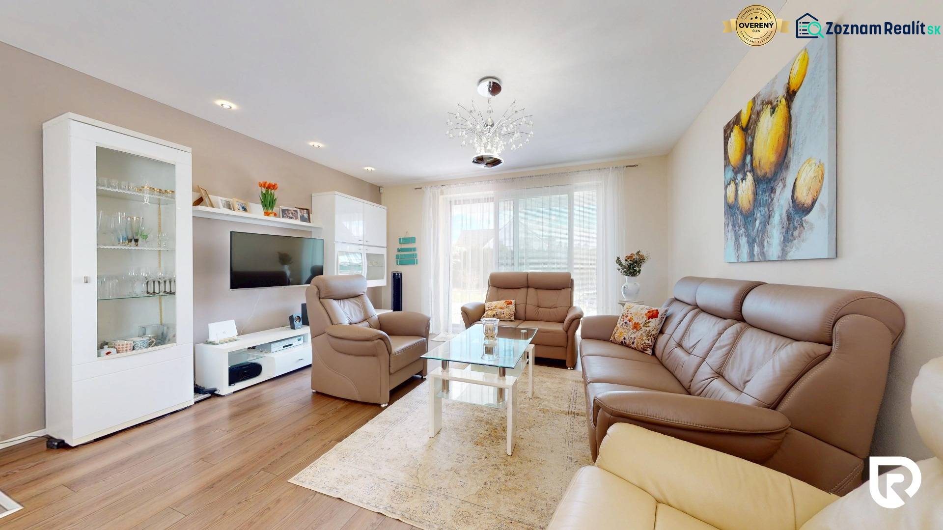 Living room of a family house with leather sofas, a glass table, and a wooden-patterned floor.