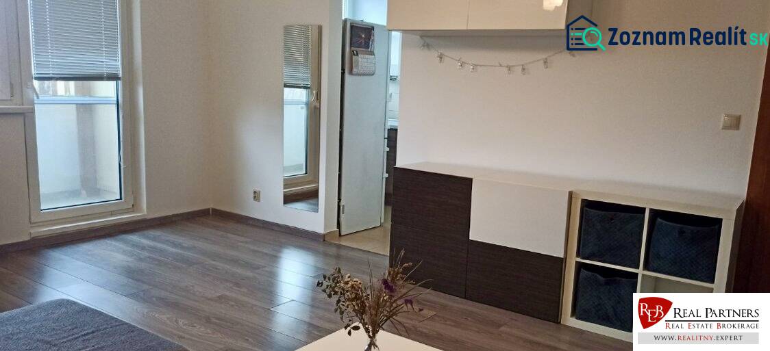 Living room in a two-room apartment with a wooden decor floor and access to the balcony.