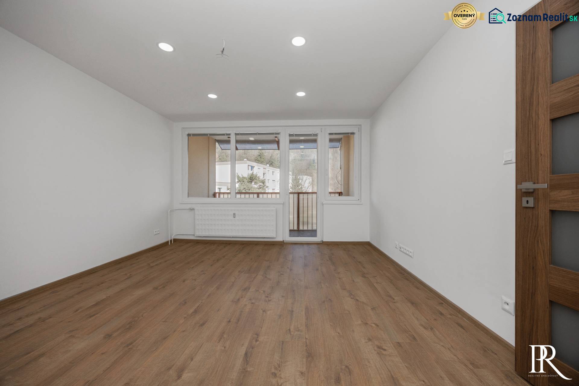 A bright room in a 3-room apartment with a wooden decor floor and balcony doors.