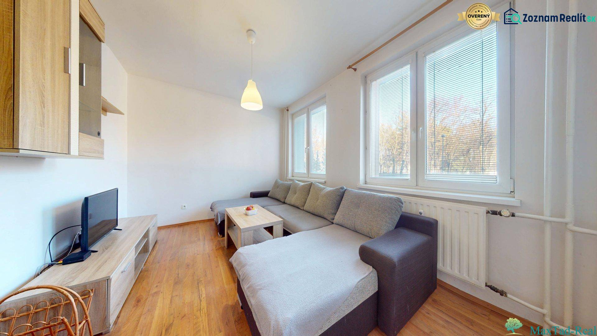 Living room in a 3-room apartment with a sofa, TV, and wooden decor flooring.