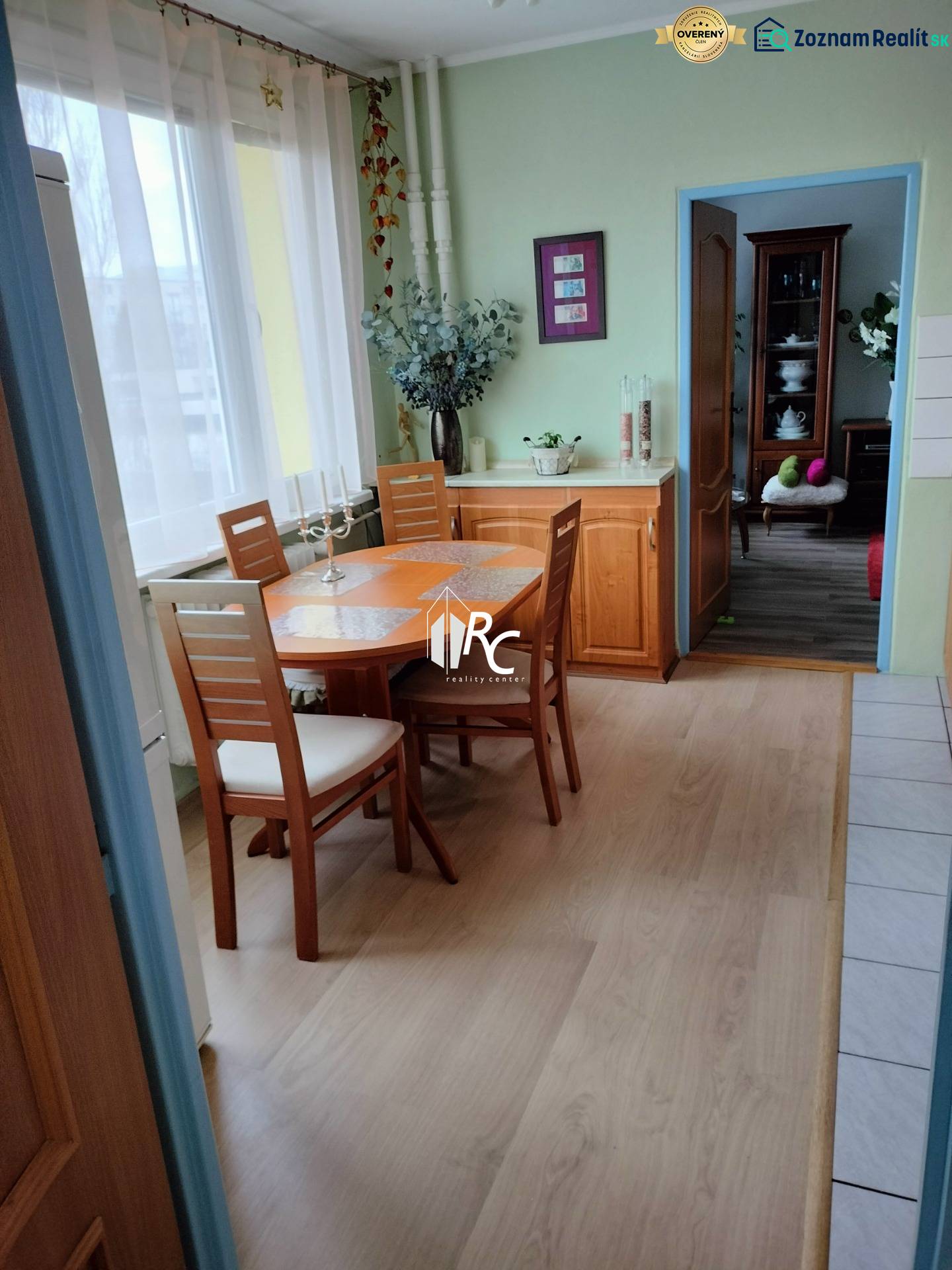 Dining area in a 2-room apartment with a wooden decor floor and light furniture.
