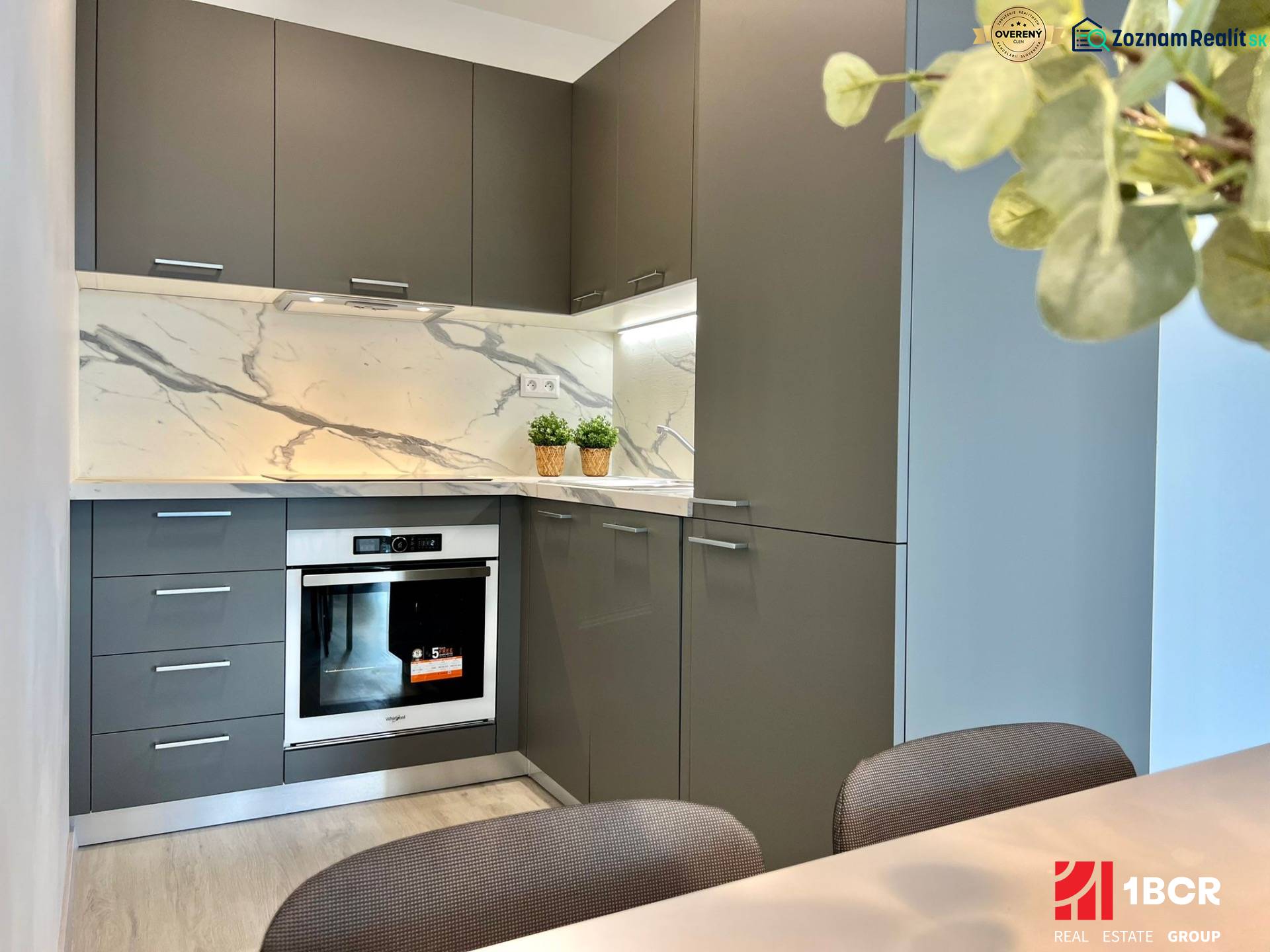 A kitchen in a 2-room apartment with stone cladding and gray cabinets.