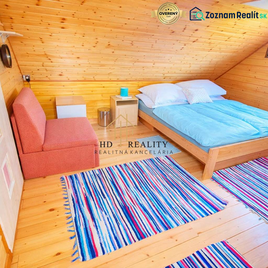 Attic cabin with a bed, sofa, wooden decor flooring, and striped carpet.